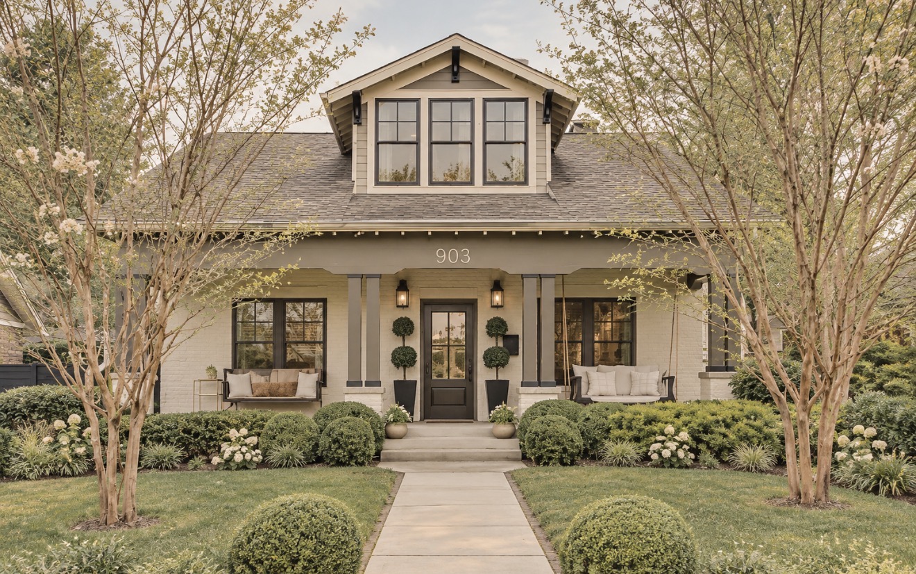 Cream brick craftsman bungalow with a full front porch, swing bed, potted topiaries and boxwood-lined walkway